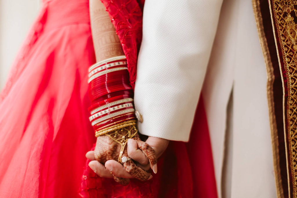 Bride and groom hands held together during traditional South Asian wedding. Photo by OkCrowe Photography.