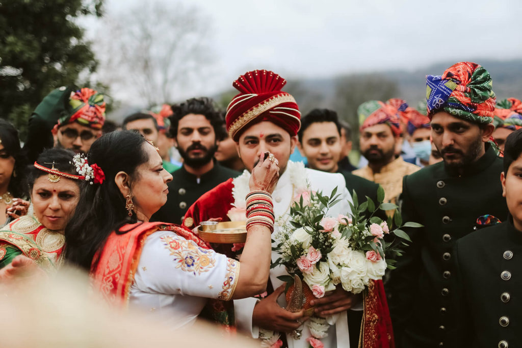 Groom being offered food during baraat. Photo by OkCrowe Photography.