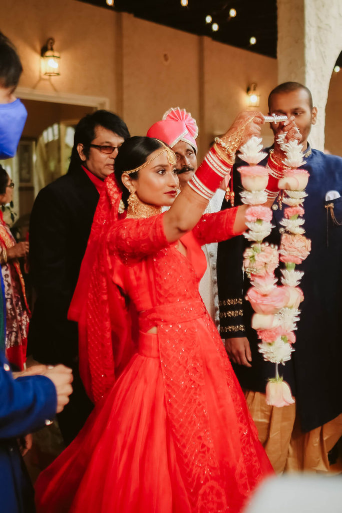 Indian bride holding a flower garland. Photo by OkCrowe Photography.