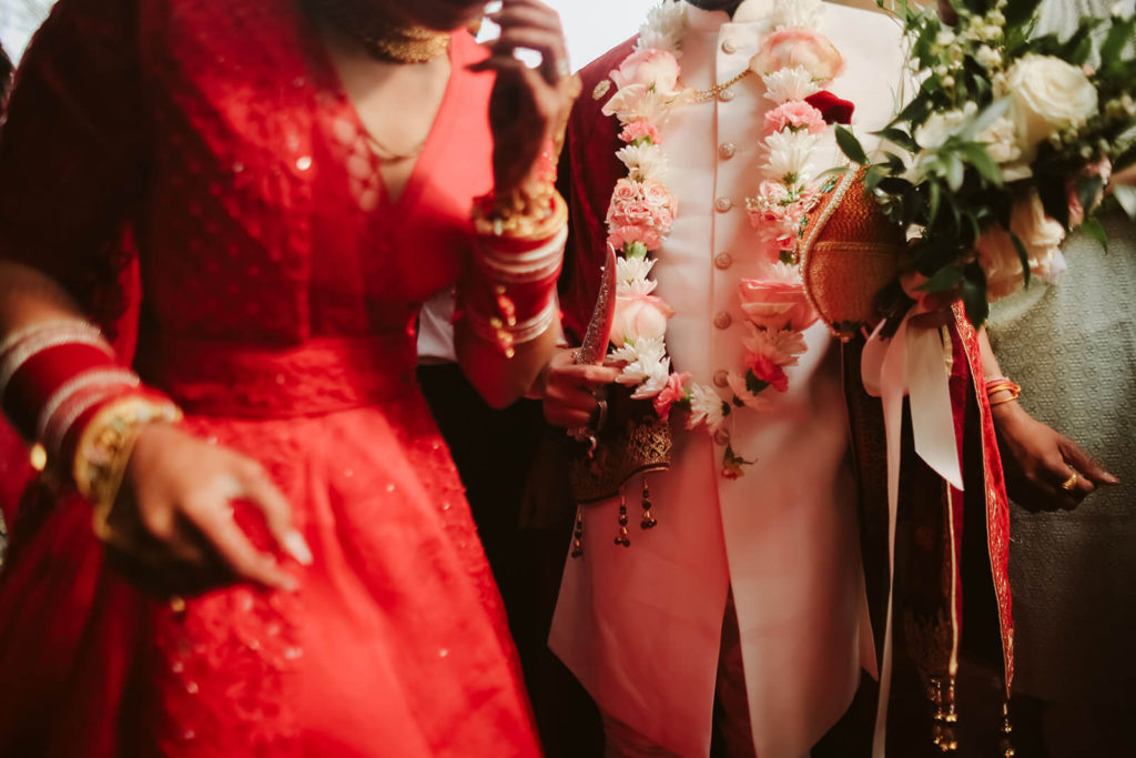 Indian bride wearing a traditional red wedding dress with guests. Photo by OkCrowe Photography.