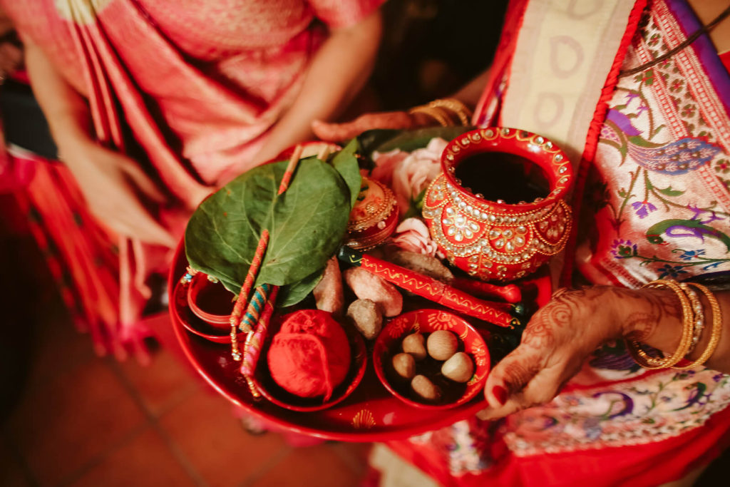 Wedding guest holding tray of blessings and offering during an Indian wedding. Photo by OkCrowe Photography.