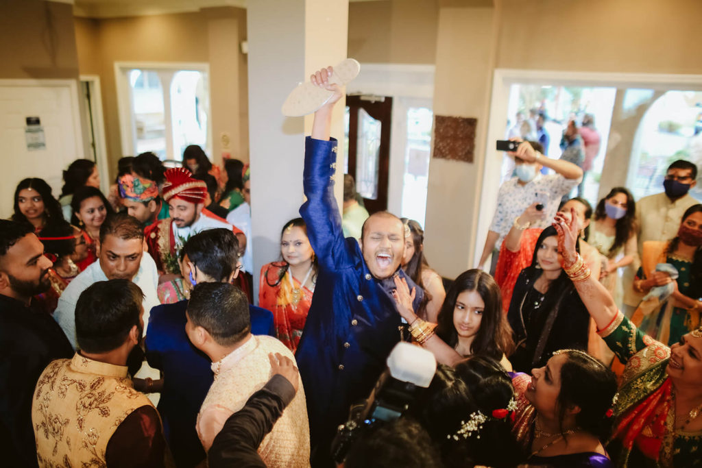 Stealing the groom's shoes during a traditional Indian wedding ceremony. Photo by OkCrowe Photography.