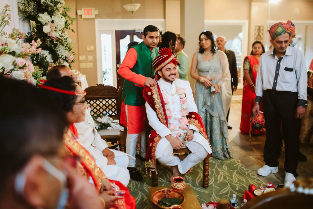 Indian groom surrounded by guests before a traditional Indian wedding ceremony. Photo by OkCrowe Photography.