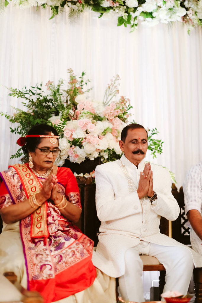 Indian wedding guests praying before wedding ceremony. Photo by OkCrowe Photography.