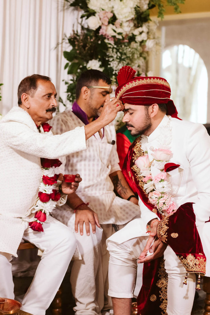 Groom's father applying tilak to his forehead. Photo by OkCrowe Photography.