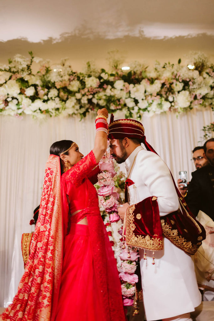 Indian bride placing a floral garland around her groom during their wedding ceremony. Photo by OkCrowe Photography.