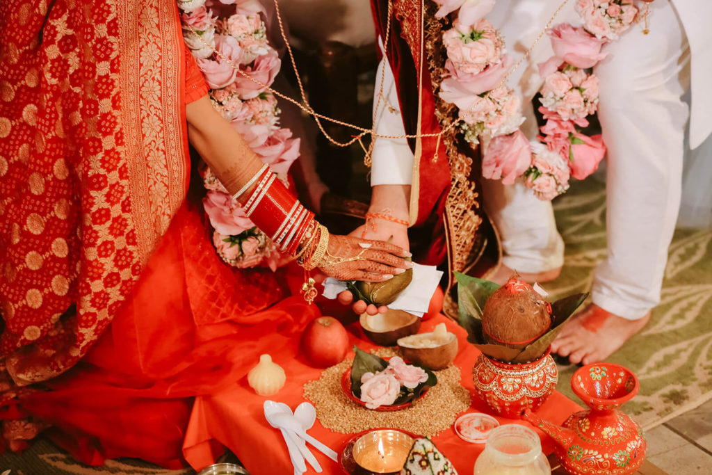 Indian bride and groom arranging offering on their wedding altar. Photo by OkCrowe Photography.