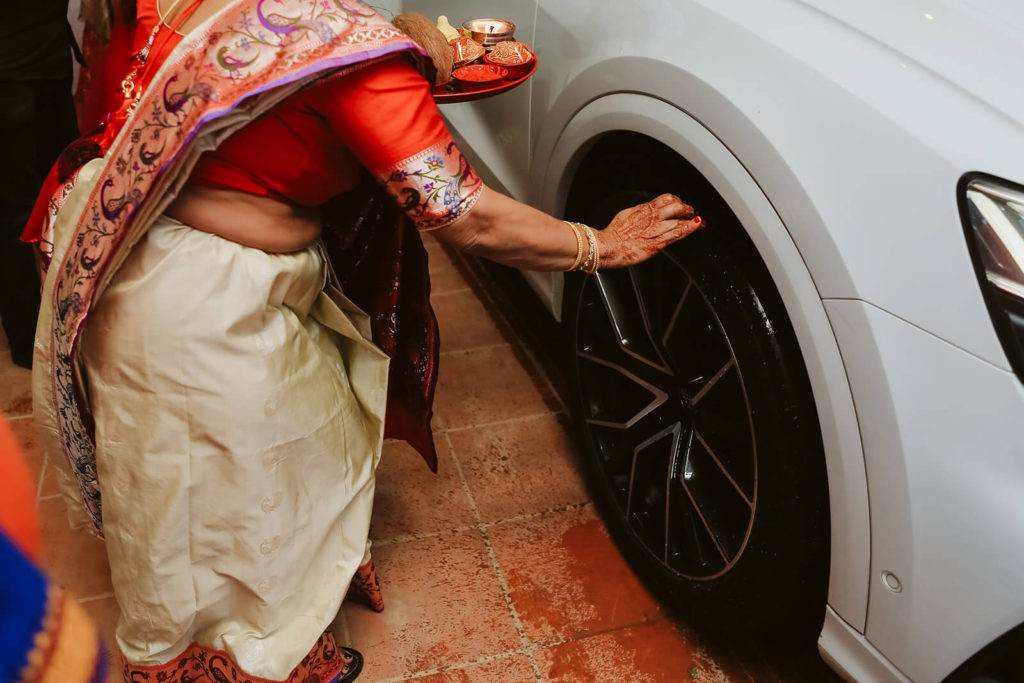 Wedding guest blessing bride and groom's car with tilak. Photo by OkCrowe Photography.