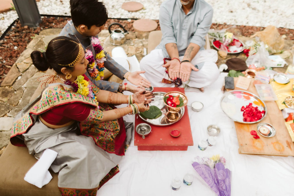 Family members blessing an offering during a South Asian wedding. Photo by OkCrowe Photography.