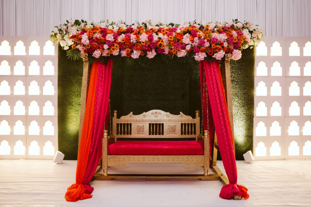 Gold bench with red cushion under a red and gold floral arbor. Photo by OkCrowe Photography.