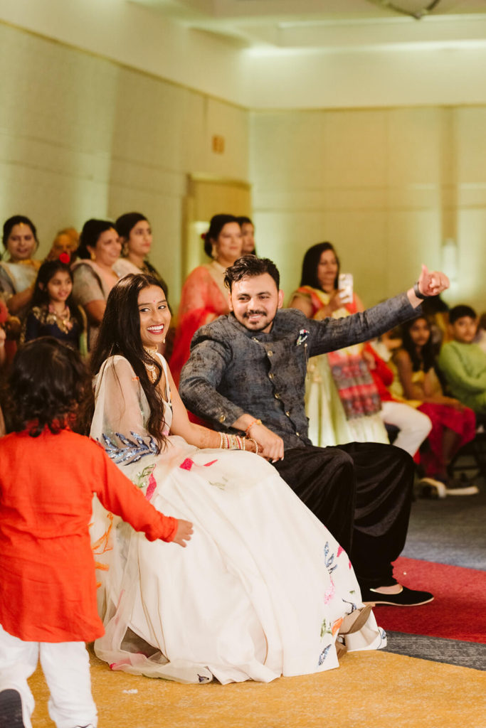 Bride and groom watching performances during Sangeet. Photo by OkCrowe Photography.