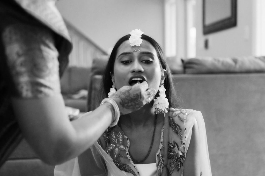 Bride being fed during Pithi ceremony. Photo by OkCrowe Photography.