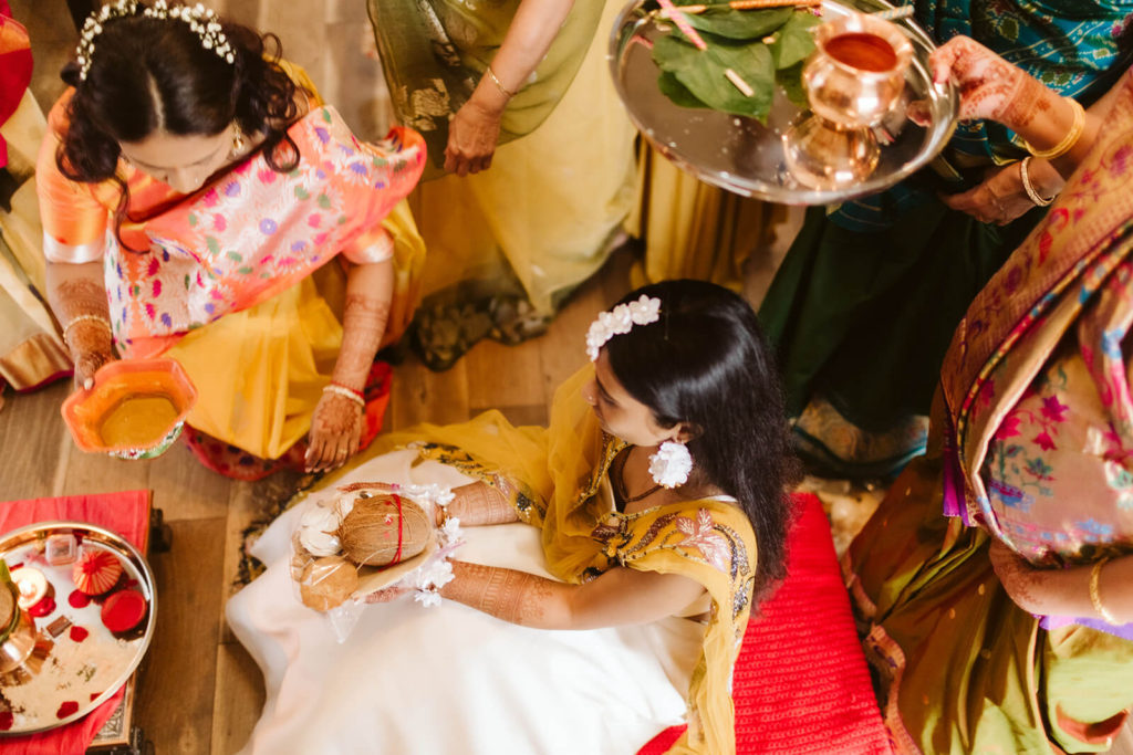 Family members helping bride prepare offerings during Pithi ceremony. Photo by OkCrowe Photography.