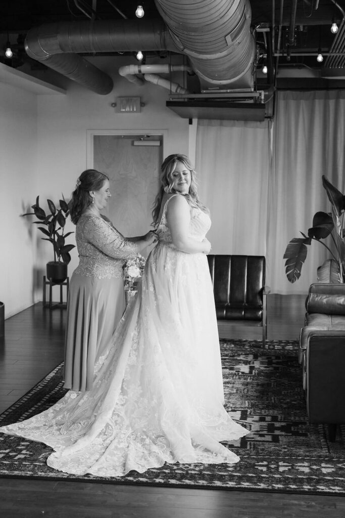 Mother of the bride helping the bride into her wedding dress in the bridal suite of the Turnbull Building in Chattanooga. Photo by OkCrowe Photography.