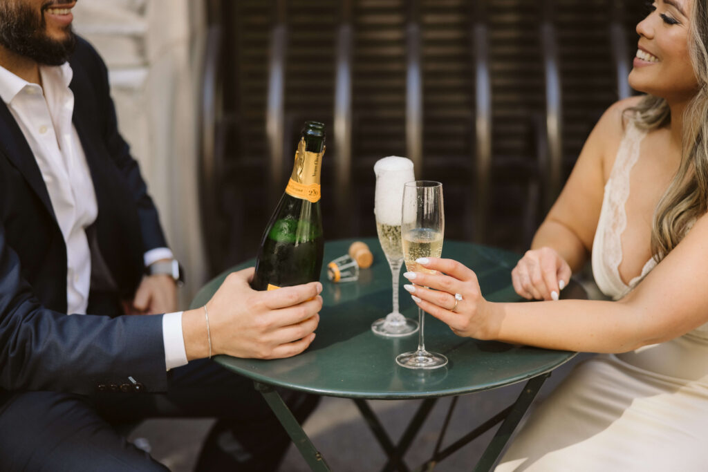 A couple sharing a champagne toast in Bryant Park during their engagement session. Photo by OkCrowe Photography. 