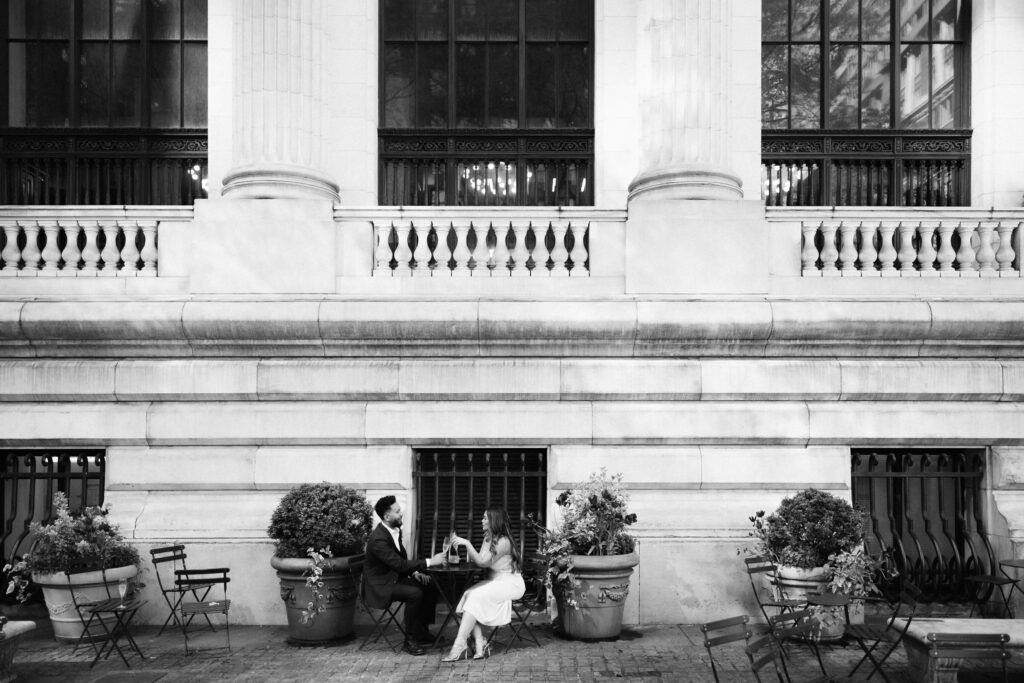 A couple sharing a champagne toast in Bryant Park during their engagement session. Photo by OkCrowe Photography. 