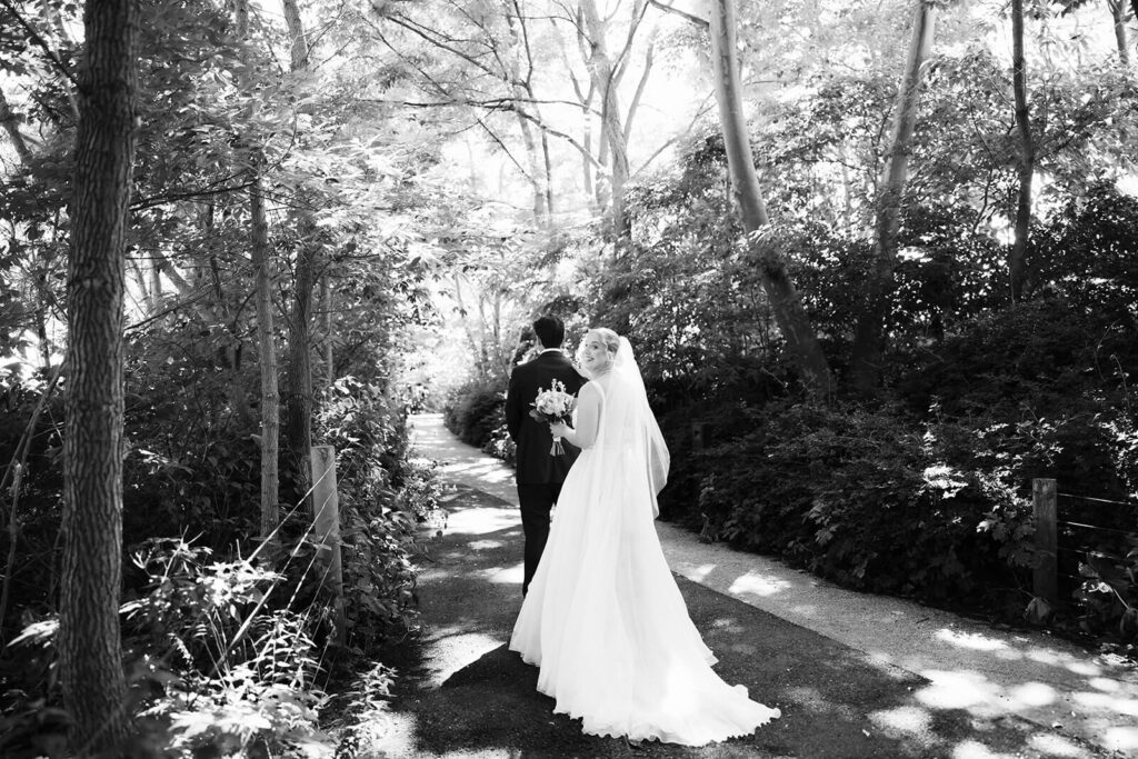 Bride and groom first look along a  forested path in Brooklyn Bridge Park. Photo by OkCrowe Photography. 