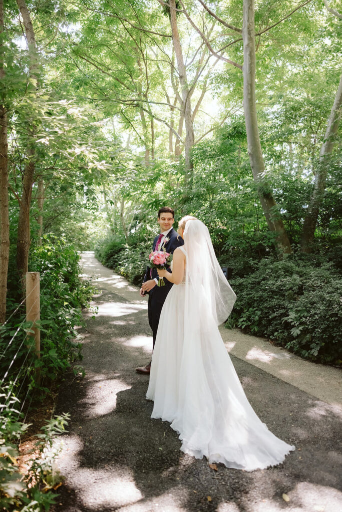 Bride and groom first look along a  forested path in Brooklyn Bridge Park. Photo by OkCrowe Photography. 