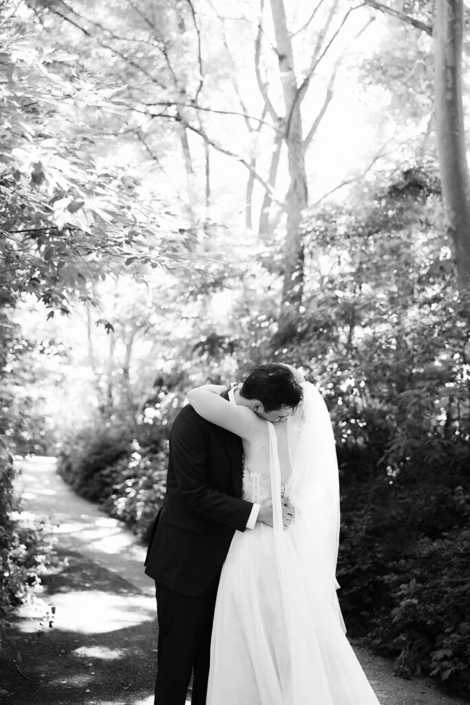 Bride and groom first look along a  forested path in Brooklyn Bridge Park. Photo by OkCrowe Photography. 