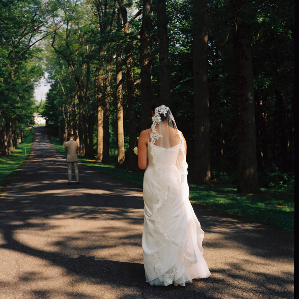 Bride and groom first look along a tree-lined road at Arrow Park. Photo by OkCrowe Photography.  