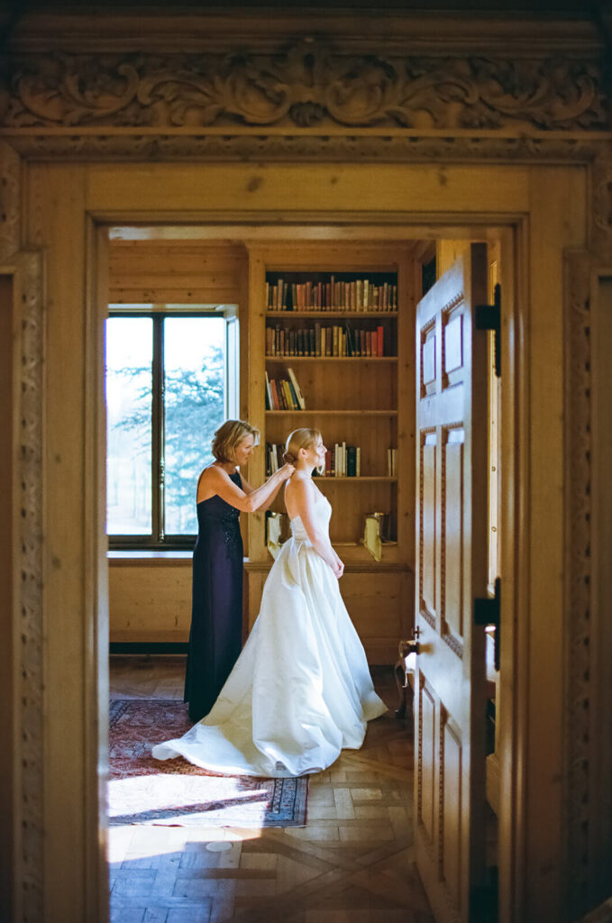 Mother of the bride helping fasten bride's wedding gown in the TPC Jasna Polana Prince Albert Suite. Photo by OkCrowe Photography.