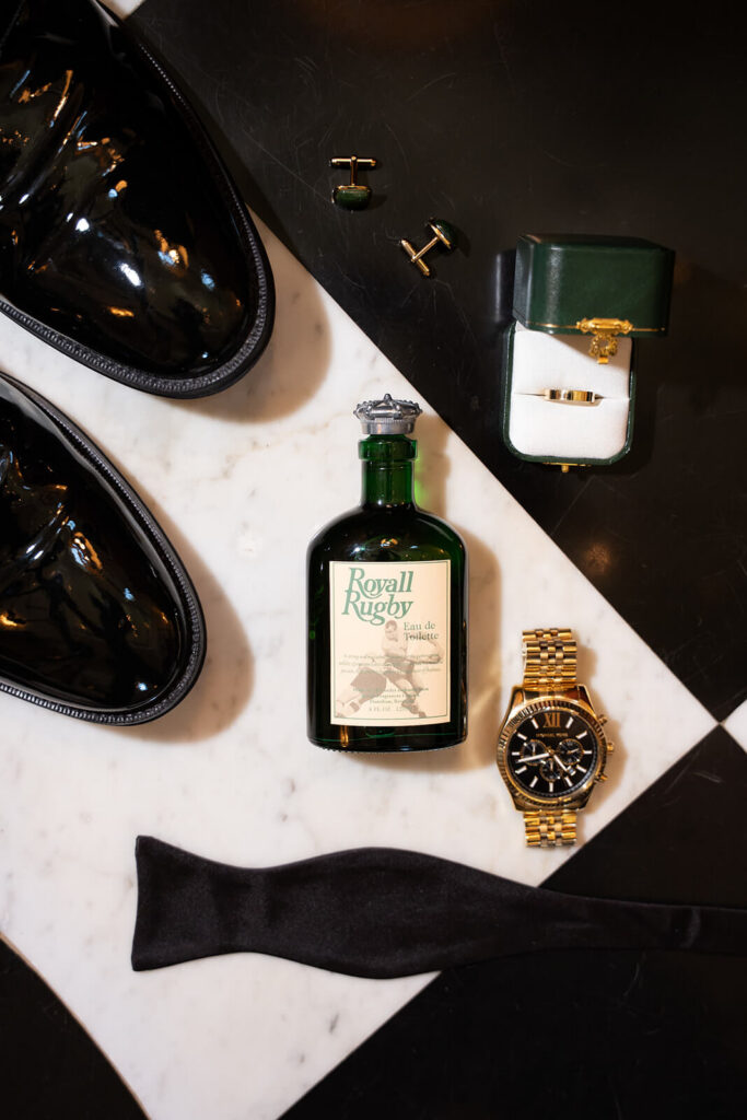 Flatlay of the groom's cologne, shoes, and wedding accessories at the Mansion at Oyster Bay. Photo by OkCrowe Photography.