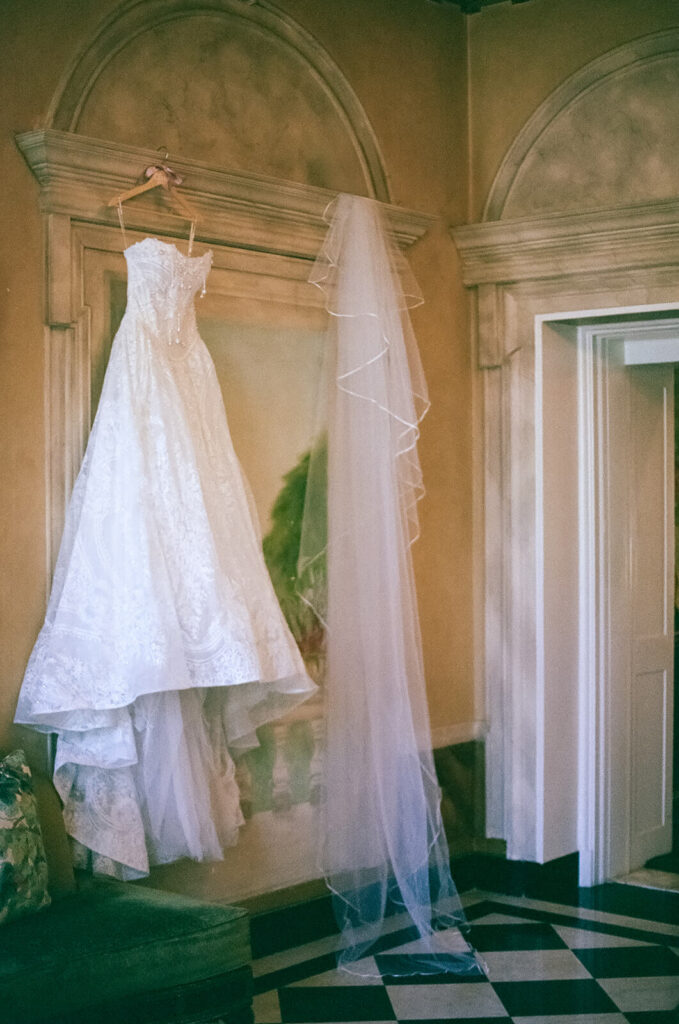 Wedding gown hanging off an antique mirror at the Mansion at Oyster Bay. Photo by OkCrowe Photography.