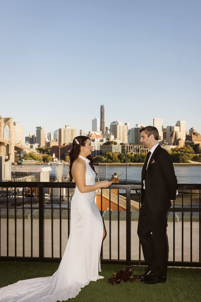 Newlyweds sharing private vows on the balcony of the 33 Seaport Hotel Brooklyn Bridge Grand Terrace Suite. Photo by OkCrowe Photography.