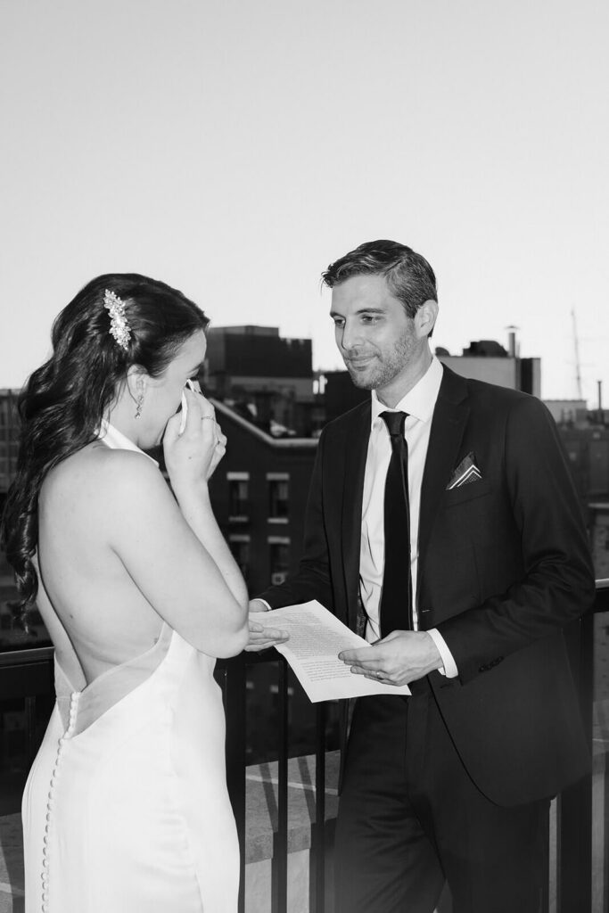Newlyweds sharing private vows on the balcony of the 33 Seaport Hotel Brooklyn Bridge Grand Terrace Suite. Photo by OkCrowe Photography.