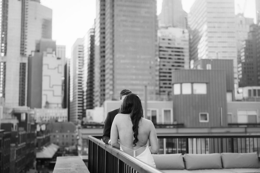 Newlyweds sharing private vows on the balcony of the 33 Seaport Hotel Brooklyn Bridge Grand Terrace Suite. Photo by OkCrowe Photography.